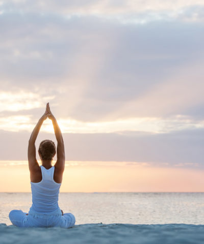 Caucasian woman practicing yoga at seashore